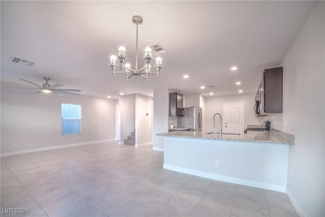 kitchen featuring hanging light fixtures, light stone counters, kitchen peninsula, ceiling fan with notable chandelier, and appliances with stainless steel finishes