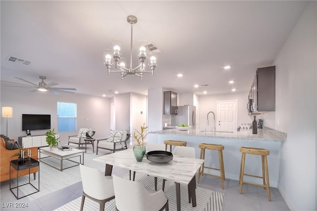 tiled dining area featuring ceiling fan with notable chandelier and sink