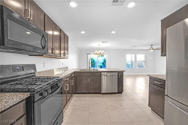 kitchen with black appliances, ceiling fan with notable chandelier, sink, decorative light fixtures, and kitchen peninsula