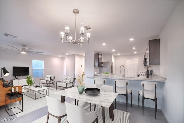 tiled dining space with ceiling fan with notable chandelier and sink