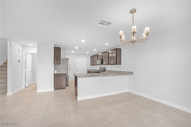 kitchen featuring light stone counters, a notable chandelier, kitchen peninsula, dark brown cabinets, and appliances with stainless steel finishes