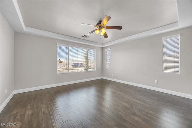 spare room featuring a tray ceiling, ceiling fan, and dark wood-type flooring