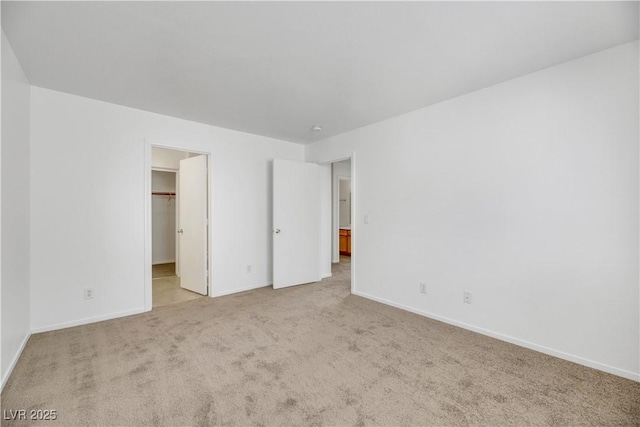 unfurnished bedroom with a walk in closet, light carpet, and a closet