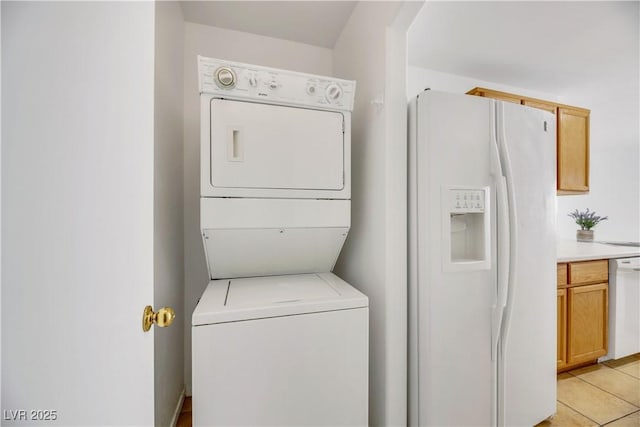 washroom with stacked washer and dryer and light tile patterned flooring