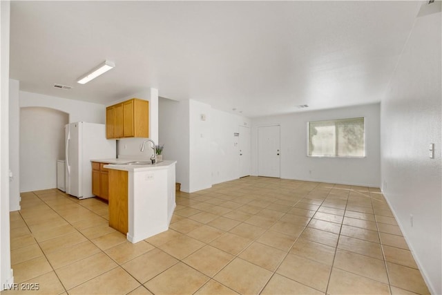 kitchen featuring kitchen peninsula, light tile patterned floors, white fridge, and sink