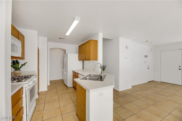 kitchen featuring light tile patterned flooring, white appliances, and sink