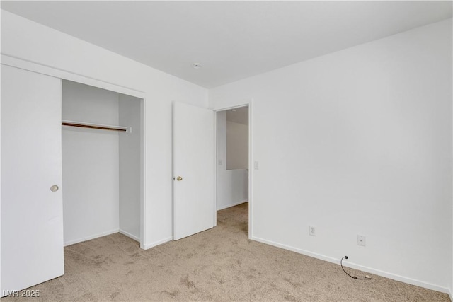 unfurnished bedroom with light carpet and a closet