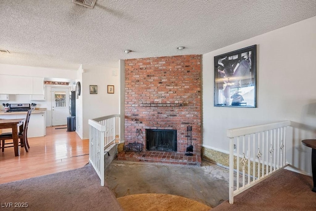 living room featuring a textured ceiling, light hardwood / wood-style flooring, and a brick fireplace