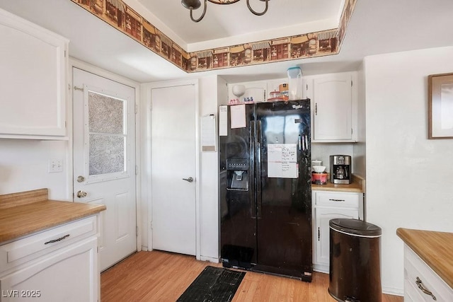 3609 Woodglen Ct, Las Vegas, NV 89108 - kitchen with black fridge, light wood-style flooring, white cabinetry, and light countertops