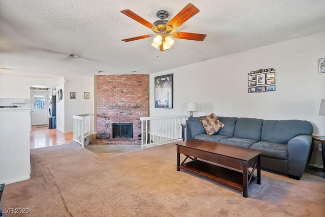 carpeted living room featuring ceiling fan, a fireplace, and a textured ceiling