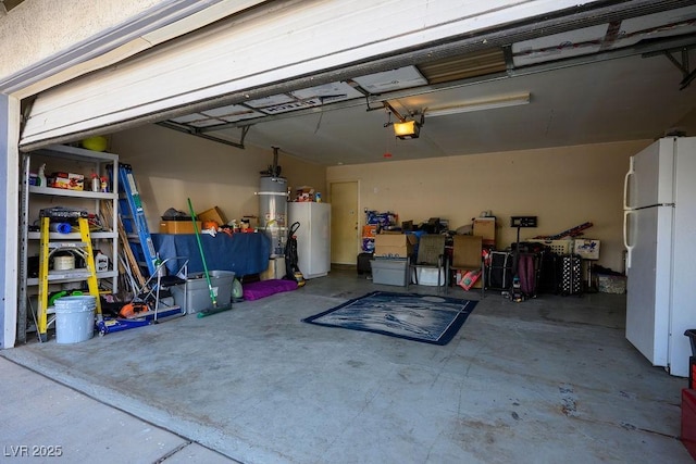 garage featuring water heater, a garage door opener, and white refrigerator