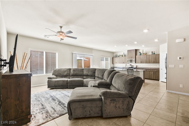 living room featuring light tile patterned floors, ceiling fan, and sink