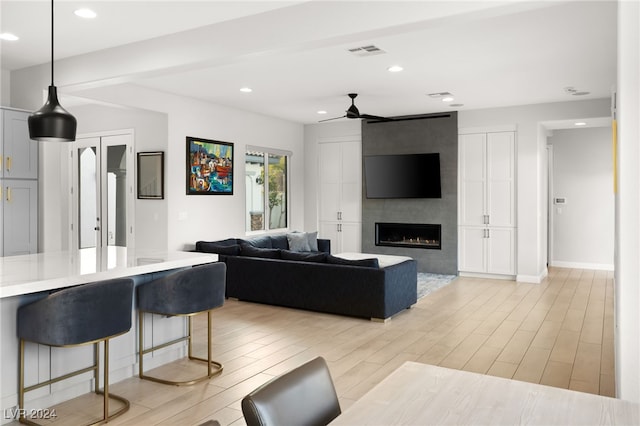 living room featuring a fireplace, light wood-type flooring, and ceiling fan