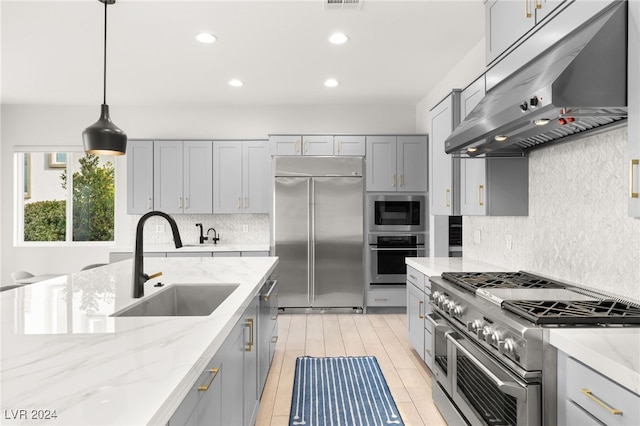 kitchen with built in appliances, pendant lighting, gray cabinetry, and sink