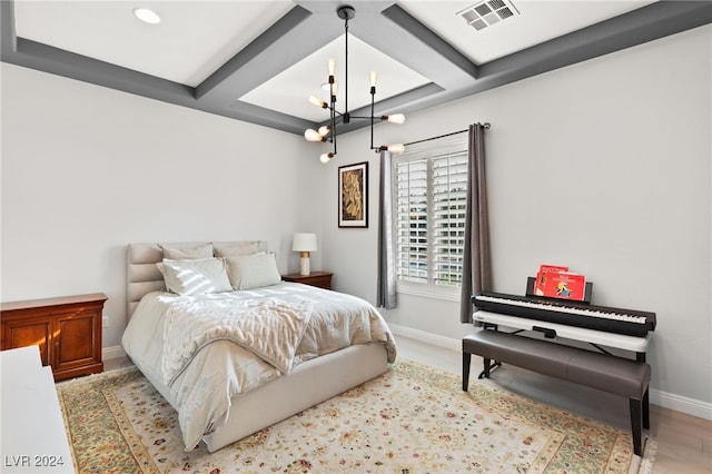 bedroom featuring light hardwood / wood-style flooring, a chandelier, and coffered ceiling