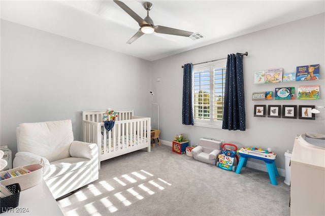 carpeted bedroom with a nursery area and ceiling fan