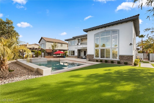 back of house featuring a pool with hot tub, a patio area, a yard, and a balcony