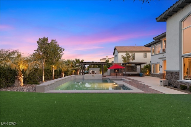 pool at dusk with a lawn and a patio area