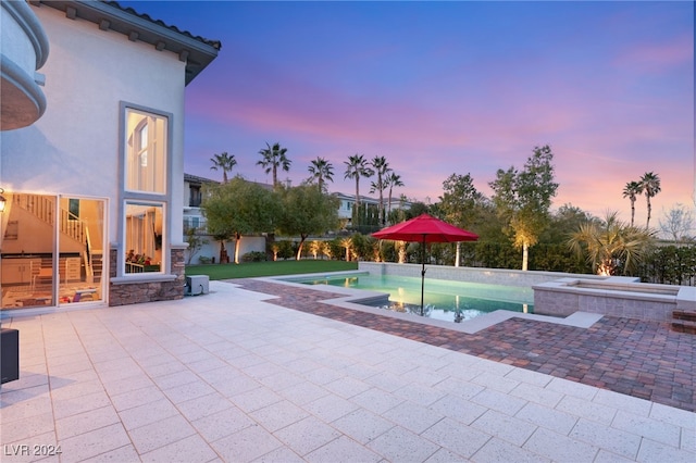 pool at dusk featuring a patio area