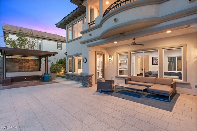 patio terrace at dusk featuring ceiling fan, a balcony, and an outdoor hangout area