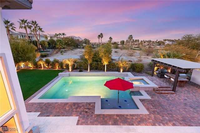 pool at dusk with a lawn, an in ground hot tub, and a patio