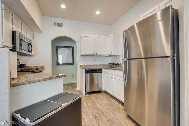 kitchen featuring white cabinets, light stone counters, and appliances with stainless steel finishes