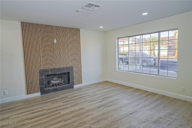 unfurnished living room with a tile fireplace and light hardwood / wood-style floors