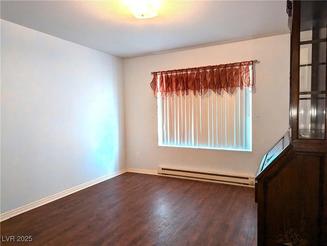 empty room with dark hardwood / wood-style flooring and a baseboard heating unit