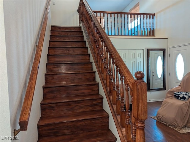 stairway featuring hardwood / wood-style flooring and a towering ceiling