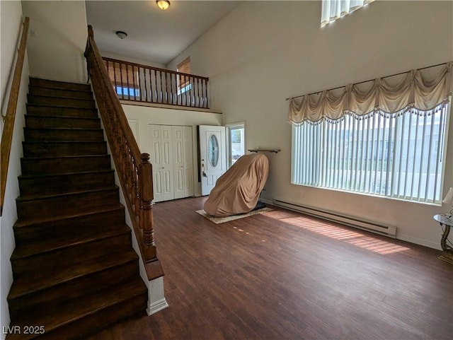 2327 Iron Dr, Ely, NV 89301 - entrance foyer featuring baseboard heating, wood finished floors, stairs, and a towering ceiling