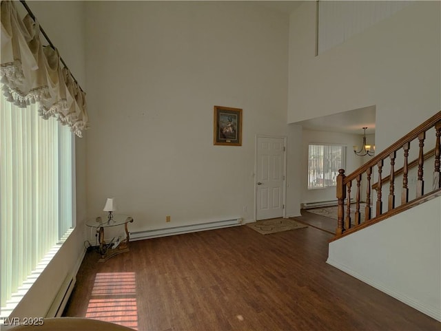 2327 Iron Dr, Ely, NV 89301 - foyer entrance featuring a chandelier, wood finished floors, a towering ceiling, a baseboard heating unit, and stairs