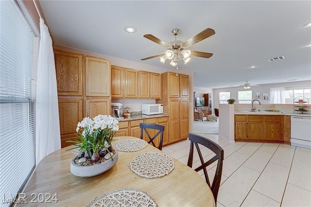 dining space featuring light tile patterned flooring, ceiling fan, and sink