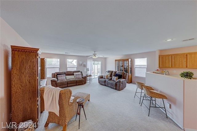 living room featuring ceiling fan, a healthy amount of sunlight, and light colored carpet