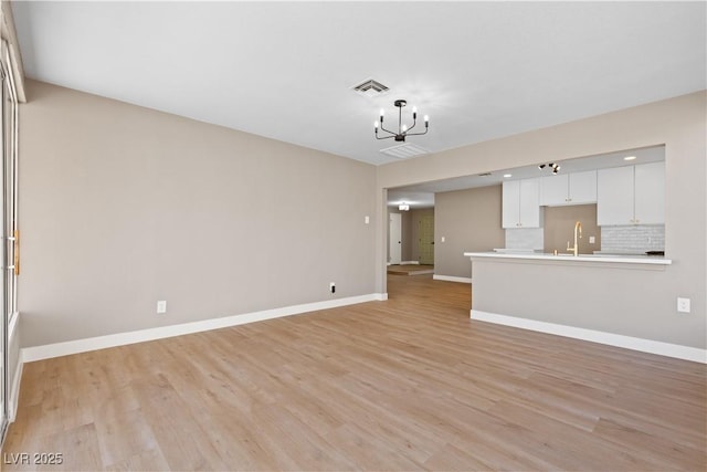 unfurnished living room with light hardwood / wood-style floors and a notable chandelier