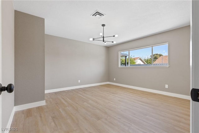 spare room with light hardwood / wood-style flooring and a chandelier