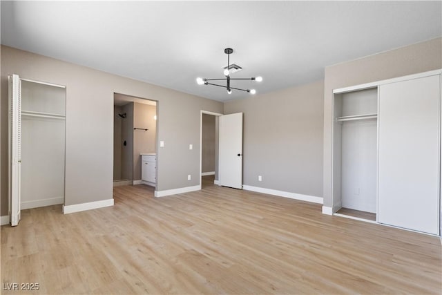 unfurnished bedroom featuring a chandelier, two closets, light hardwood / wood-style flooring, and ensuite bath