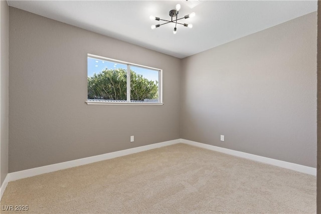 carpeted empty room featuring a chandelier