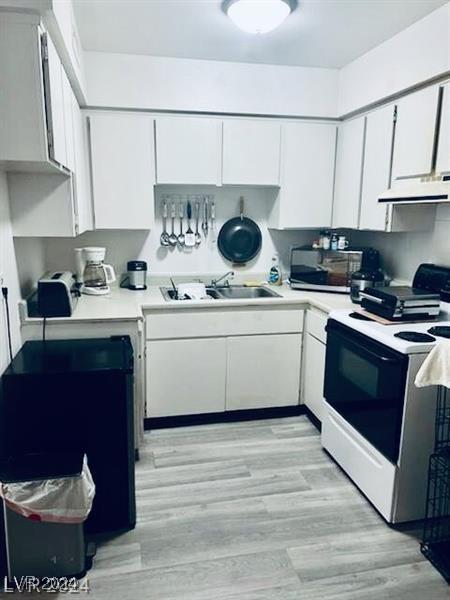 kitchen featuring white appliances, ventilation hood, sink, light hardwood / wood-style floors, and white cabinetry