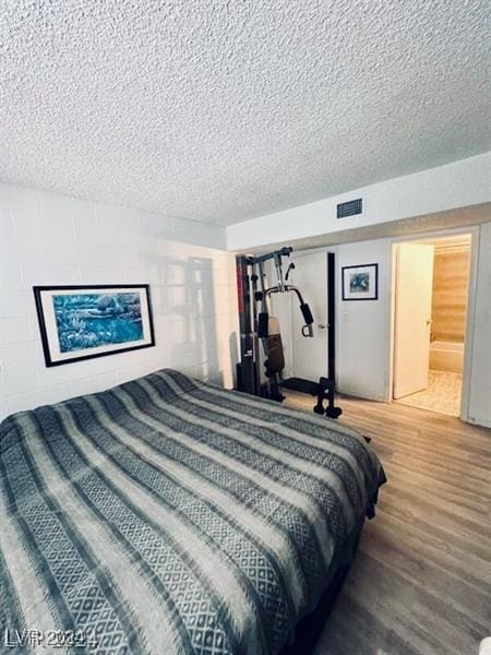 bedroom featuring hardwood / wood-style floors and a textured ceiling