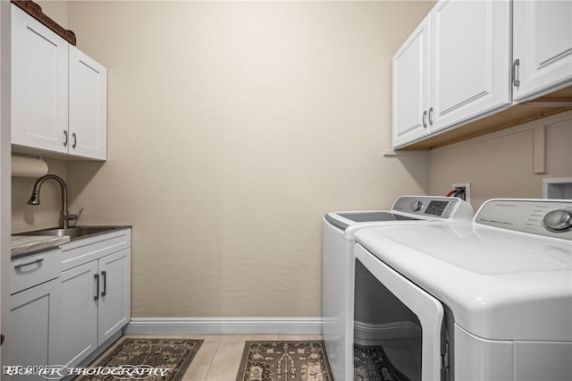 washroom with cabinets, light tile patterned floors, washer and clothes dryer, and sink