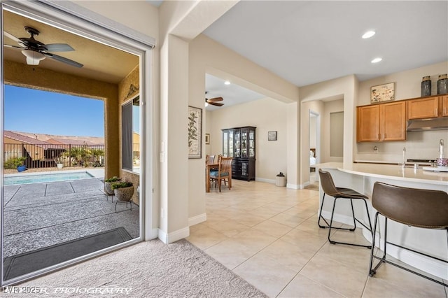 kitchen with ceiling fan, a healthy amount of sunlight, light tile patterned floors, and a breakfast bar area