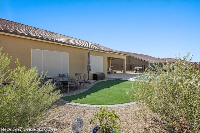 back of property with a yard and a patio