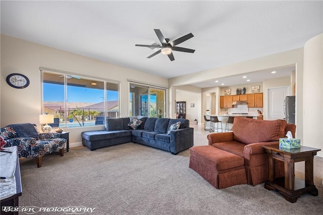 living room featuring a mountain view, light colored carpet, and ceiling fan