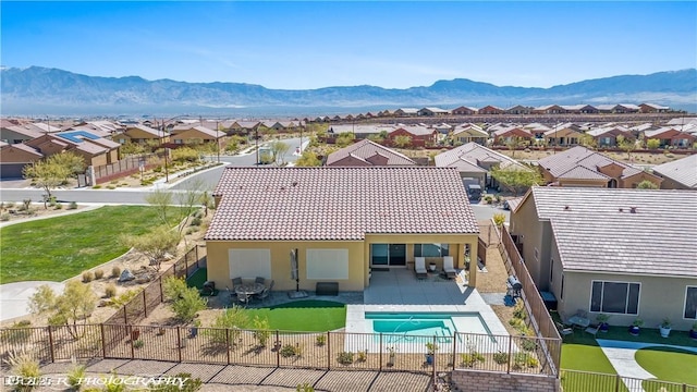 back of property with a mountain view and a patio