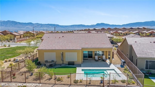 back of house with a fenced in pool, a patio area, and a mountain view