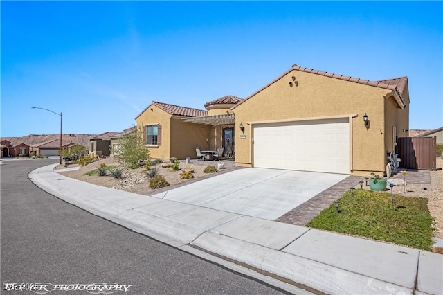 mediterranean / spanish-style house featuring a tile roof, an attached garage, concrete driveway, and stucco siding