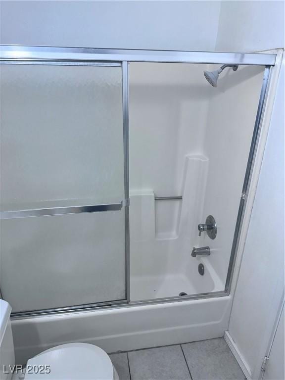 bathroom featuring tile patterned flooring, enclosed tub / shower combo, and toilet