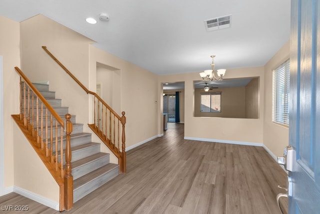 entrance foyer featuring plenty of natural light, wood-type flooring, and ceiling fan with notable chandelier