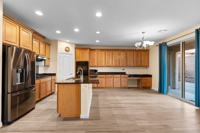 kitchen featuring stainless steel appliances, a kitchen island with sink, sink, pendant lighting, and a notable chandelier