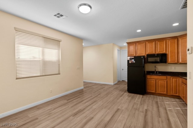 kitchen with sink, black appliances, and light hardwood / wood-style flooring